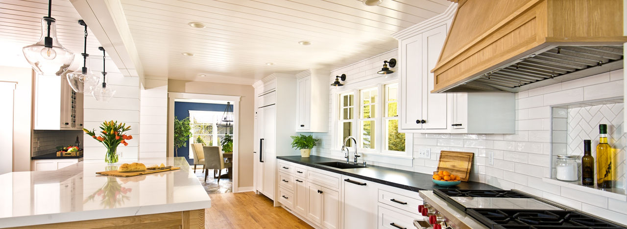 A contemporary kitchen renovation remodeling, featuring a large island, quartz counter top, hardwood floor, professional range stove and exhaust fan, kitchen sink, an open concept design to dining and living room.