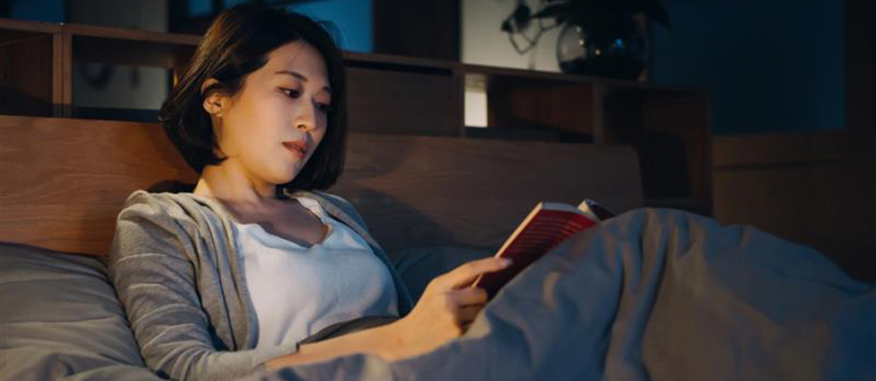 Women reading book in bed